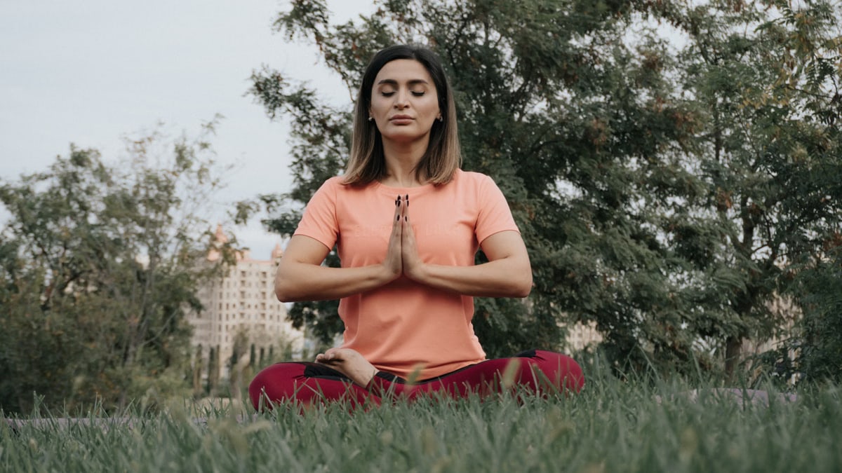Woman practicing yoga and meditation in park. Enhancing mindfulness and relaxation outdoors.